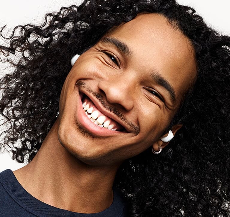 A headshot of a man wearing his Galaxy Buds plus with a huge smile, tilting his head to the right.