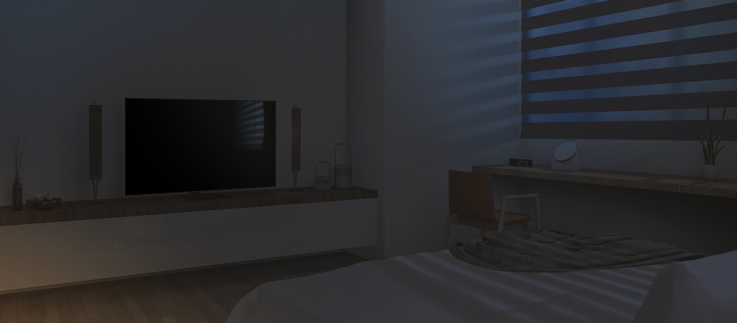 El interior de un dormitorio limpio con una cama, un televisor y otros objetos. Está amaneciendo, las persianas están cerradas y el televisor está apagado.