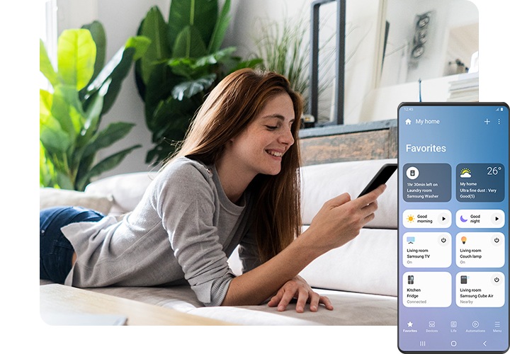 Una mujer está acostada en el sofá, sonriendo y mirando su teléfono inteligente. En el lado derecho del primer plano, una pantalla de Galaxy muestra la interfaz gráfica de usuario de la aplicación SmartThings con varios dispositivos inteligentes para el hogar conectados, su estado y otras rutinas que podrían configurarse, como “Buen día” y “Buenas noches”.