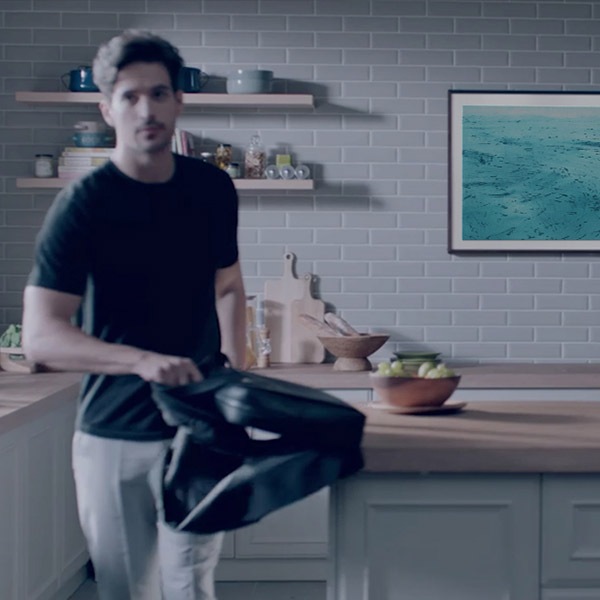 Un hombre está saliendo de la cocina en la que hay un televisor The Frame colgado.