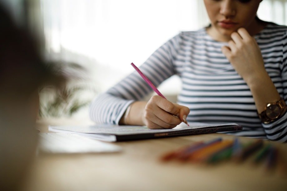Una mujer sentada en un escritorio y escribiendo algo; el primer plano de la toma está borroso