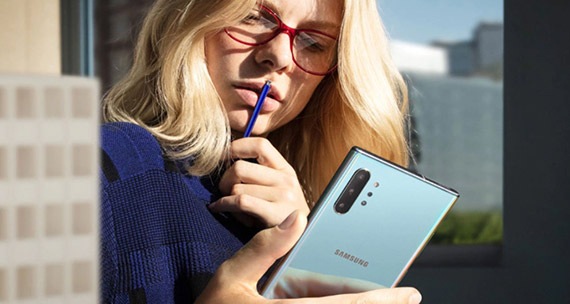 Mujer mirando intensamente la pantalla de su Galaxy Note 10, sosteniendo el S Pen contra sus labios.