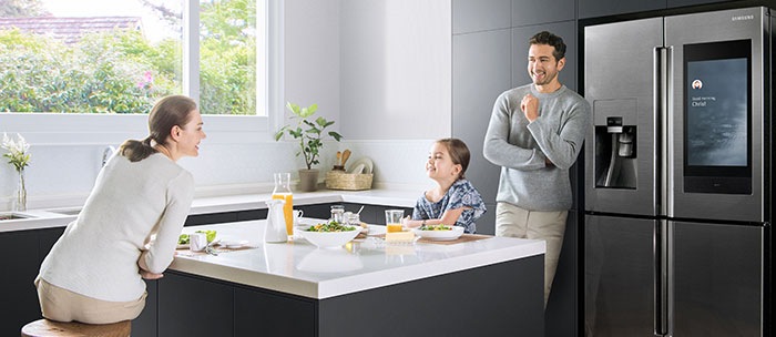 一家三口在廚房內享受早餐，邊站在Family Hub智能雪櫃前。