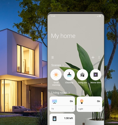 בית בן שתי קומות שהאור בו דלוק. מסך אפליקציית SmartThings מציג את ההגדרות שנקבעו עבור מצבים כמו "בוקר טוב", "ניקיון", ו"יציאה". מוצגת גם אפשרות לשליטה במכשירי חשמל כמו טלוויזיה, תאורה ומכונת כביסה.
