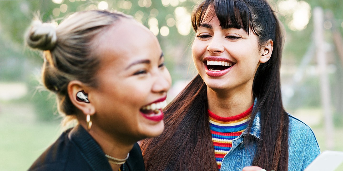 Share the music with friends. One woman is wearing Galaxy Buds Live in Mystic Black and the other is Galaxy Buds Live in Mystic Bronze.