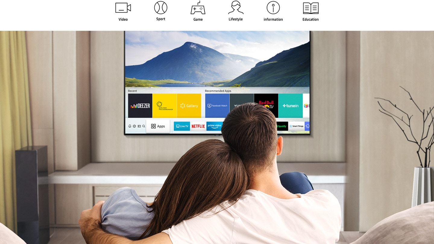 3 people in the living room, are watching Smart TV and various apps are displayed on the TV.