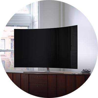 Una mesa de madera posicionada en angulo en una habitación de tonos claros con el QLED TV.