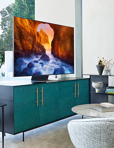 6. Una imagen de estilo de vida del nuevo QLED Q90R de Samsung de 2019. Una vista lateral del Q90R colocado sobre la mesa del televisor verde.