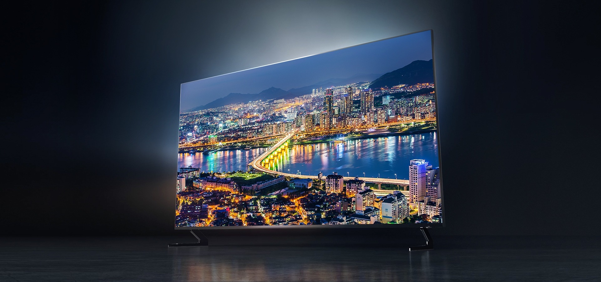 Vista en perspectiva derecha del más reciente televisor de Samsung, el nuevo QLED Q900R de Samsung de 2019 con una vista clara de la ciudad en pantalla en el televisor.