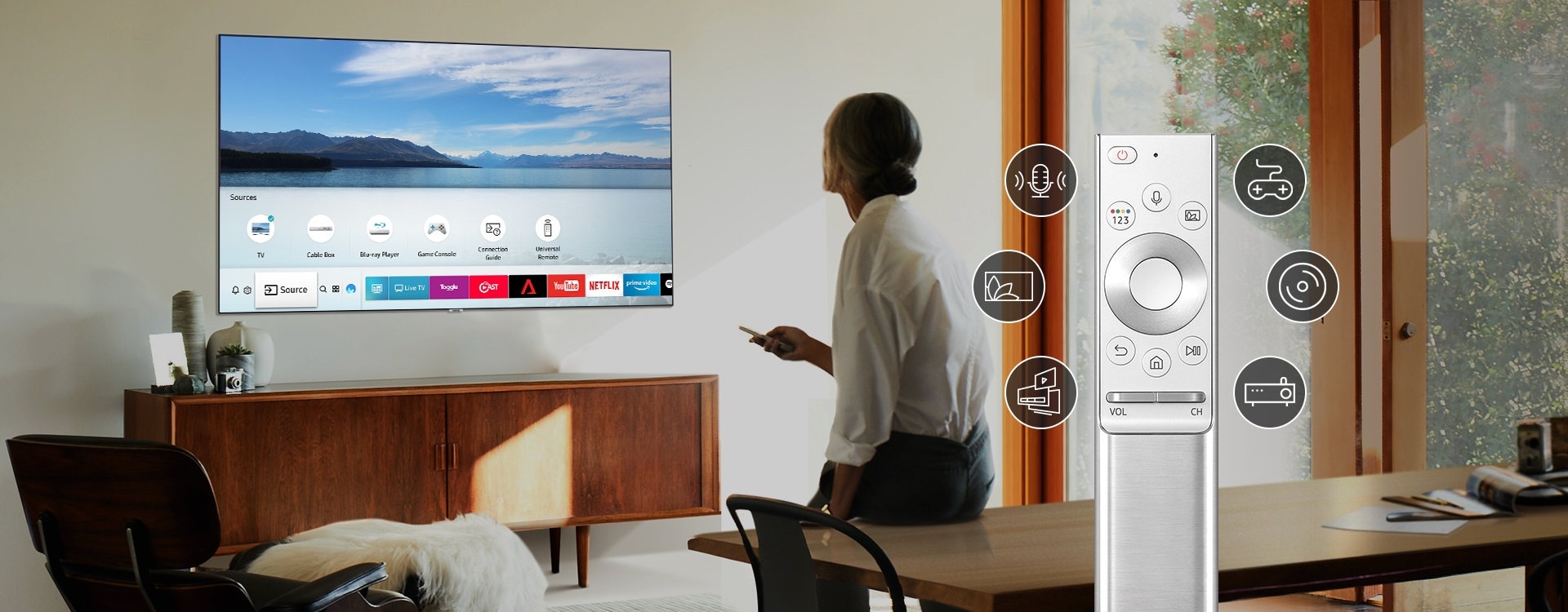 In front of the TV is a woman sitting on the desk with a remote. Next to her is an image of an enlarged remote with 6 icons. The icons represent that remote controls for several devices such as game and DVD players are integrated into one remote control. 