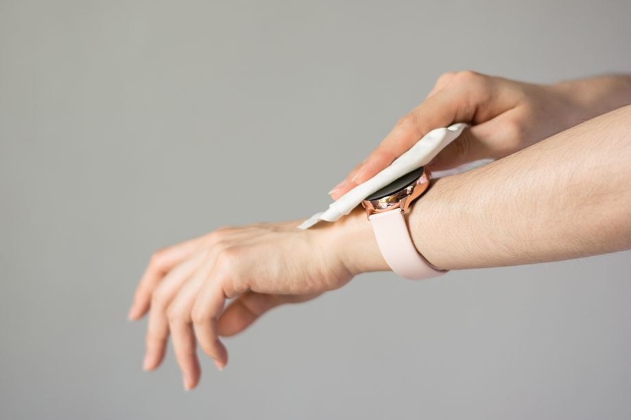 Primer plano de la mano una de mujer limpiando su Galaxy Watch Active 2 con un paño de microfibra