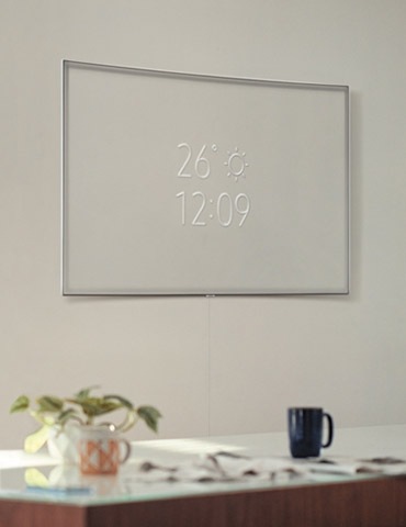 A lifestyle image of the 2018 new QLED TV Q8C. Image shows the QLED TV is mounted on the wall with its Ambient Mode. It is showing simple information such as time and weather.