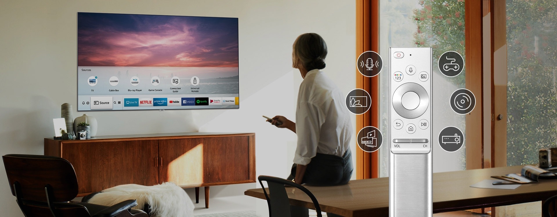 In front of the TV is a woman sitting on the desk with a remote. Next to her is an image of an enlarged remote with 6 icons. The icons represent that remote controls for several devices such as game and DVD players are integrated into one remote control.