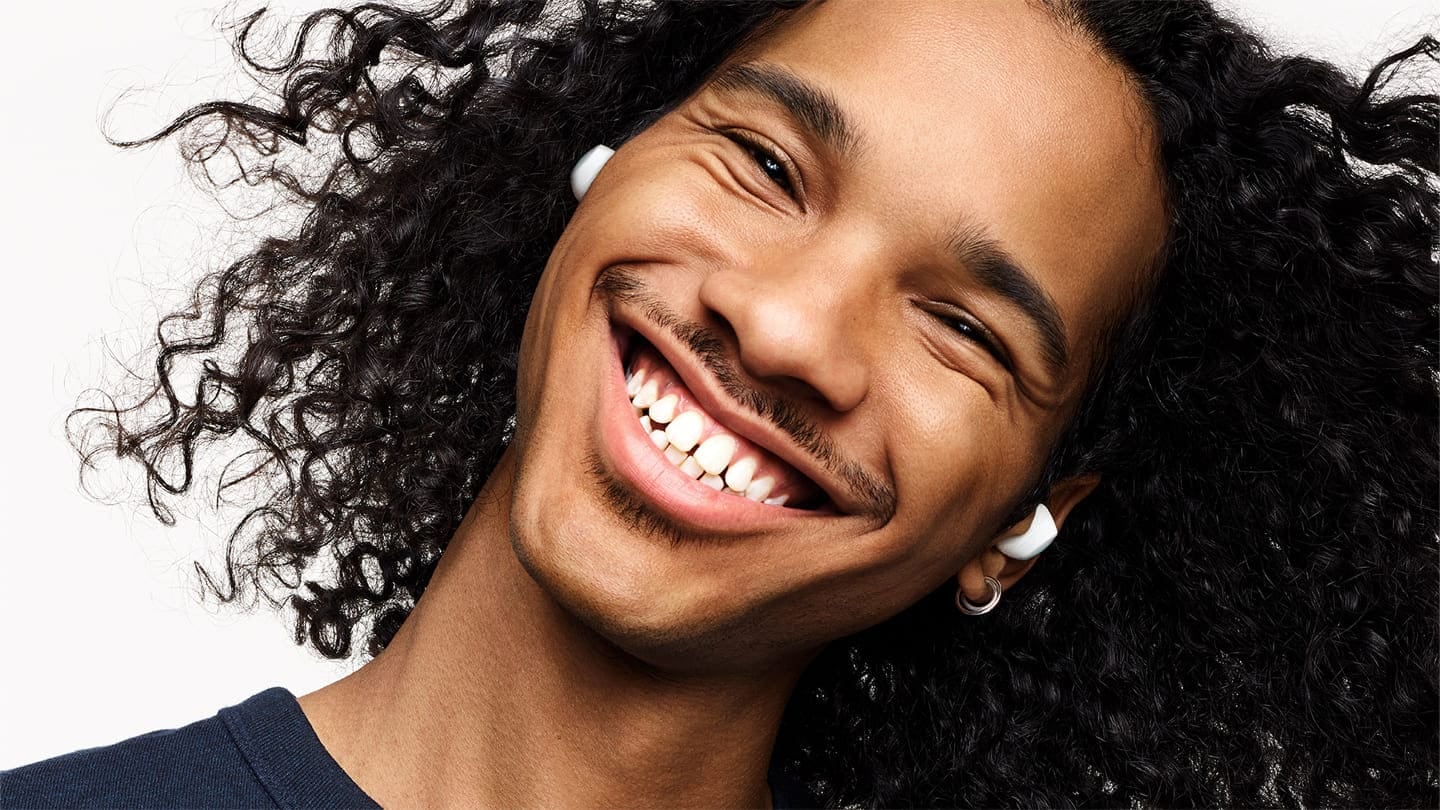 A headshot of a man wearing his Galaxy Buds plus with a huge smile, tilting his head to the right.