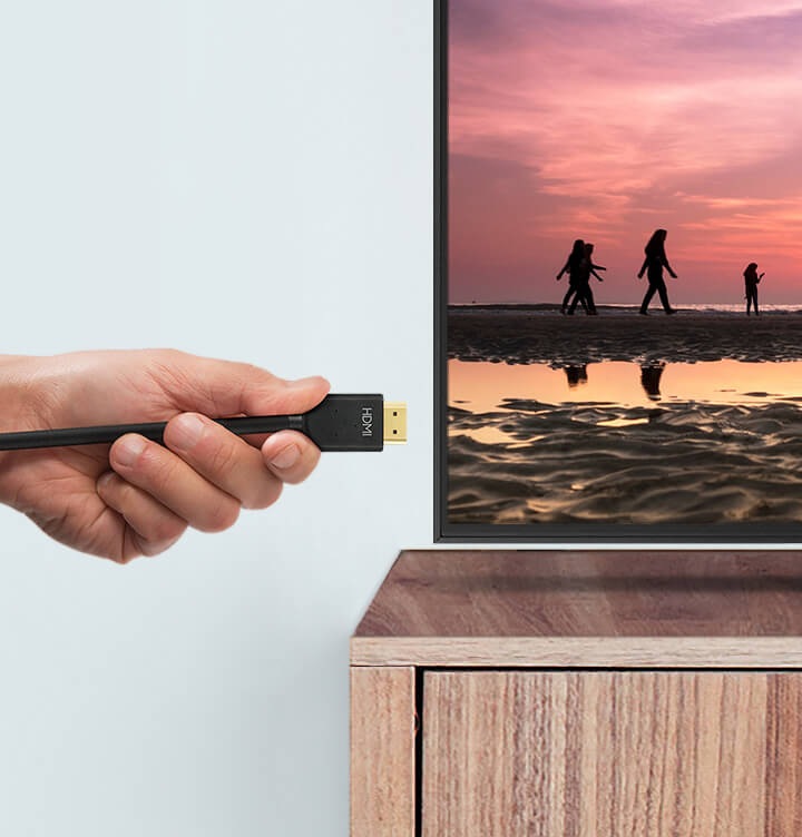 Ręka podłączająca kabel HDMI do telewizora