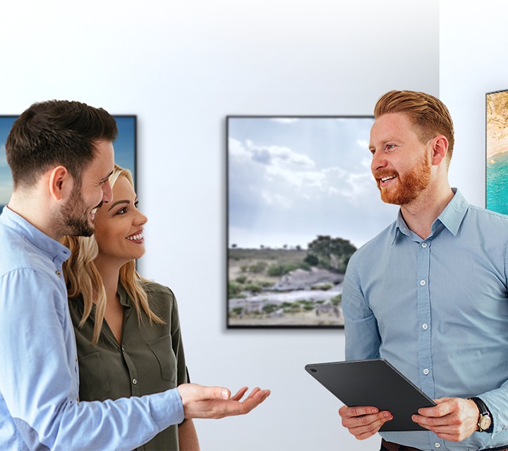 Para comprar uma nova televisão, um homem e uma mulher conversam com um representante de vendas masculino sobre os recursos da TV num showroom de TVs.