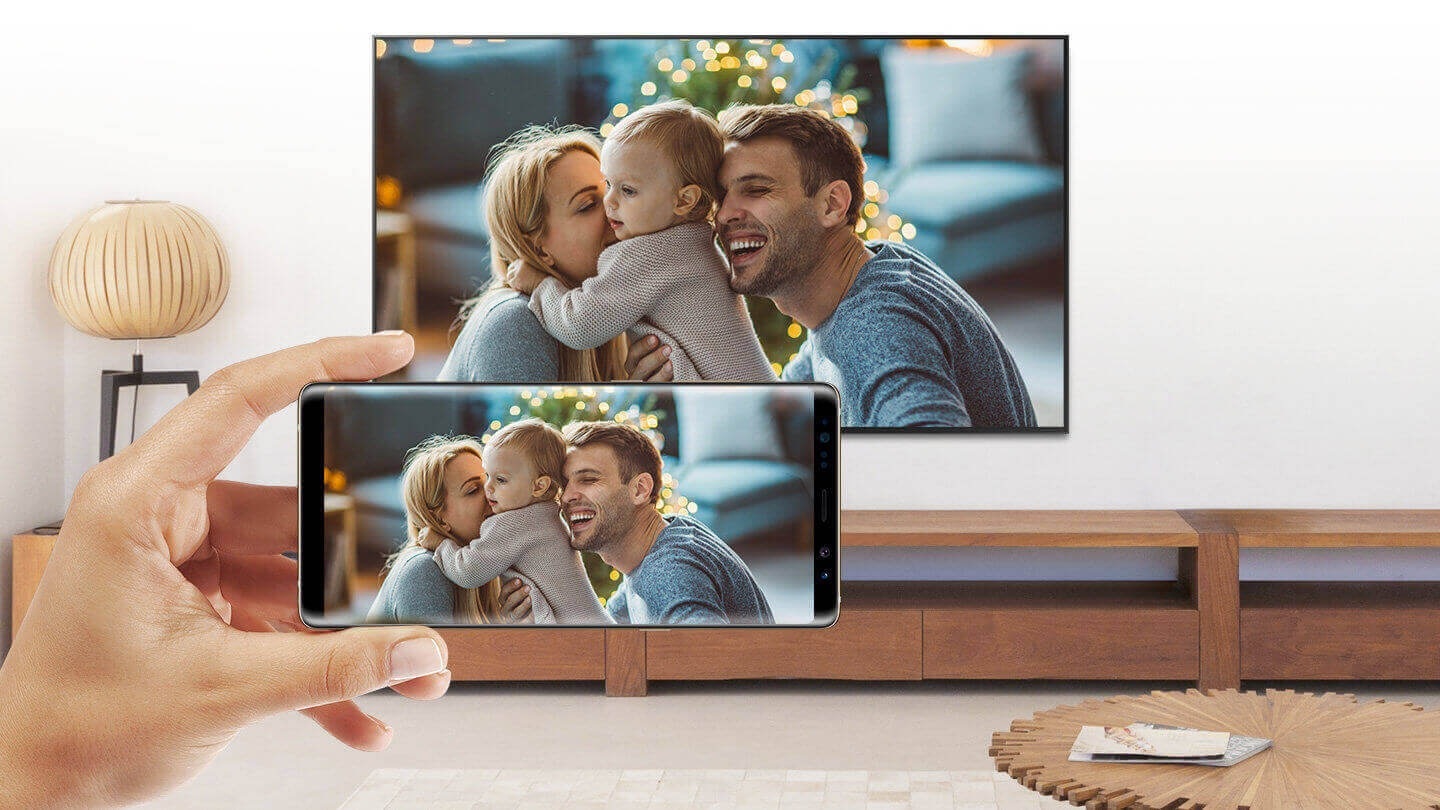 Mobilni telefon i pametni televizor dijele isti zaslon; fotografija roditelja i djeteta.