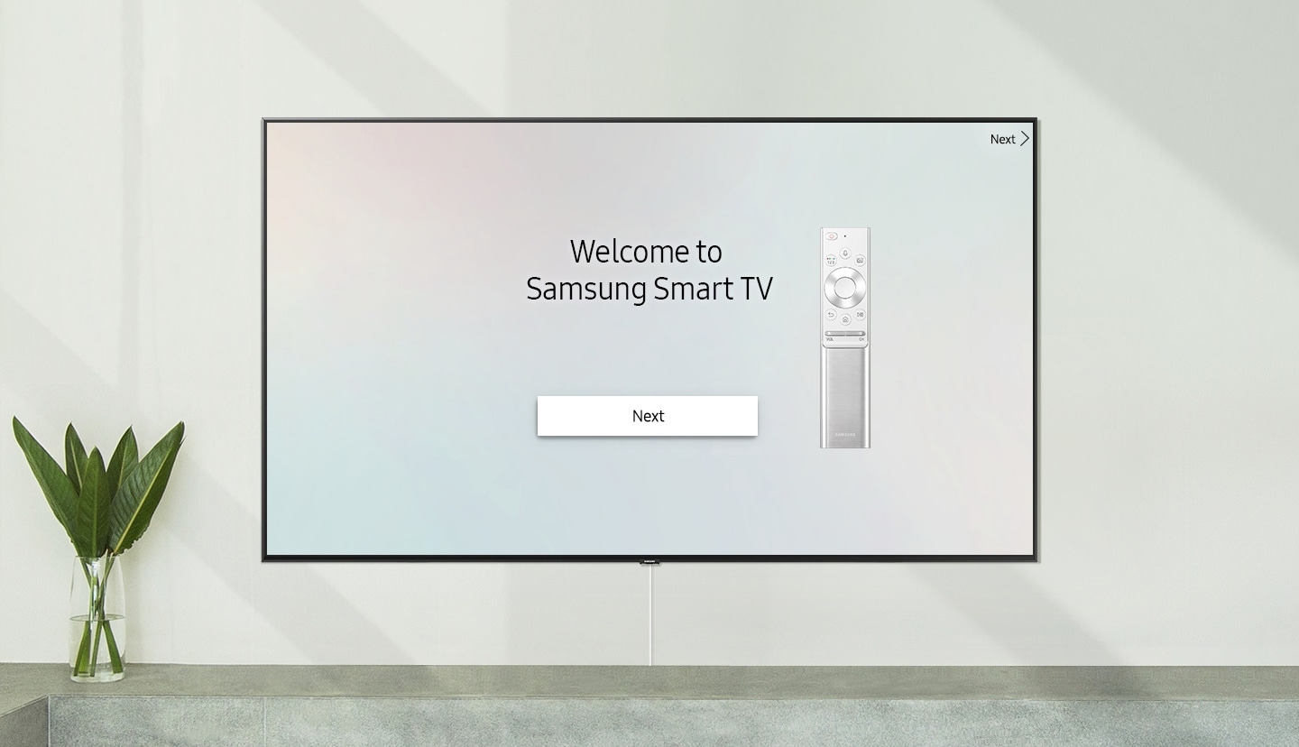 Pametni televizor postavljen na zid sa zaslonom dobrodošlice; „Dobro došli u pametni televizor Samsung” s jednim daljinskim upravljačem.