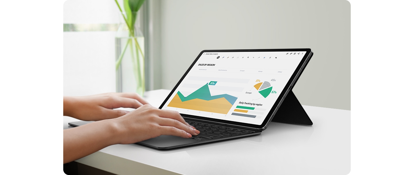 A tablet device is held up with the Book Cover Keyboard at an angle that resembles a laptop. A pair of hands are on the keyboard, busy working on a presentation. 