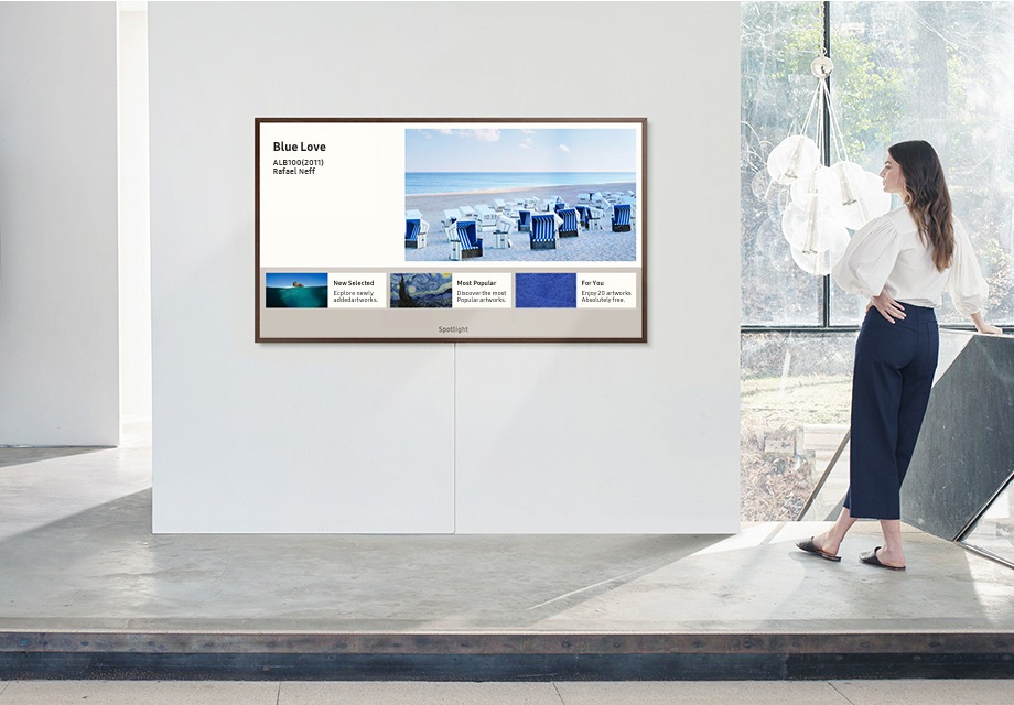امرأة في استوديو كبير مفتوح تتفحص القطع الفنية الزرقاء المتوفرة على Samsung Art Store على The Frame.