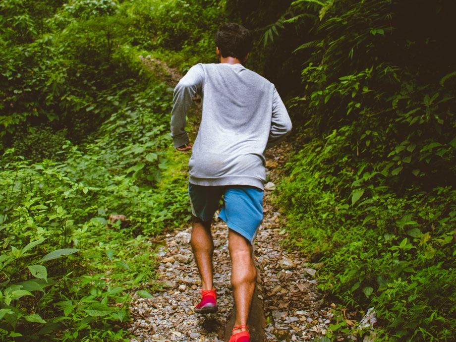 Bild på en man som springer i skogen med en svettig tröja