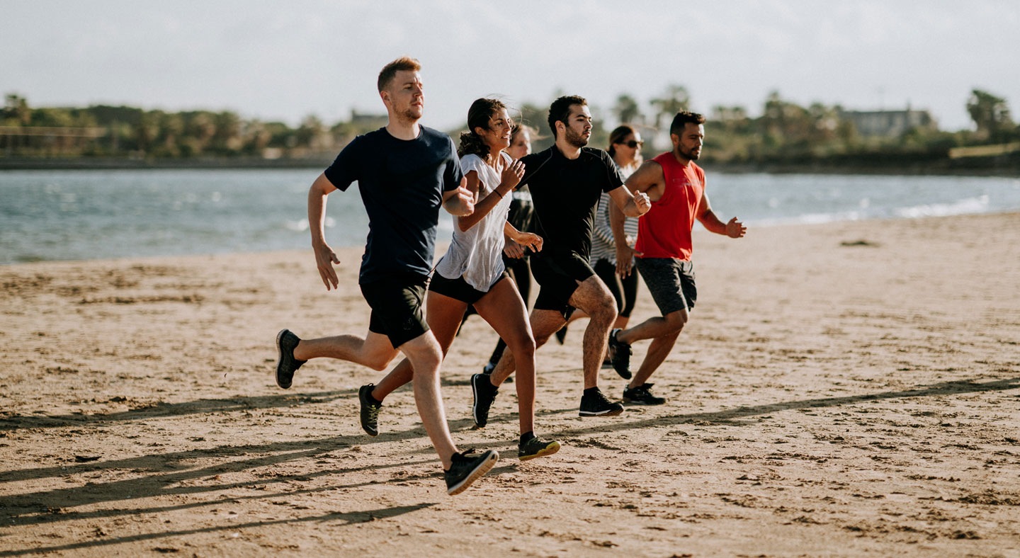 Bild på flera personer som springer på stranden