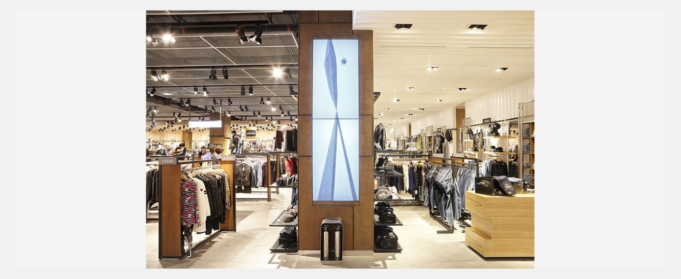 백화점 내부 쇼핑 공간 정면 기둥에 삼성 스마트 사이니지가 설치된 모습을 보여주고 있습니다.