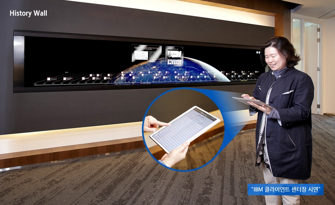 History Wall에서 IBM 클라이언트 센터장 시연으로 한 여성이 태블릿을 가지고 시연하는 모습과 태블릿 화면의 확대 모습입니다.