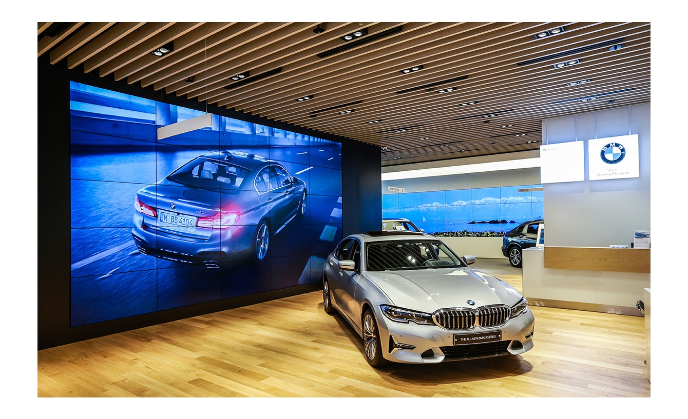 BMW 쇼룸에 삼성 스마트 사이니지 비디오월이 설치되어 있고 화면에서는 프로모션 화면을 보여주고 있습니다