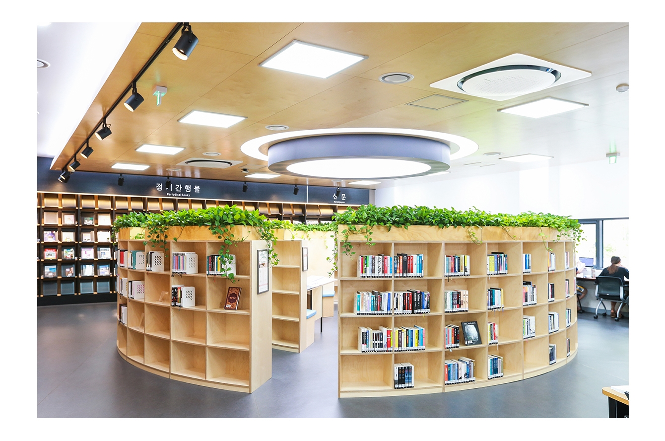 도서관의 한 공간에 나무 책장이 원형으로 놓여있고 천장에는 시스템 에어컨 360이 설치되어 있습니다