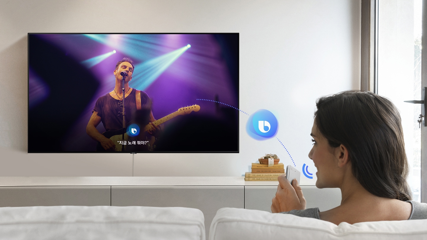 한 여성이 Bixby에게 One Remote Control을 통해 스마트 TV에 나오는 노래가 무엇인지 묻고 있습니다.