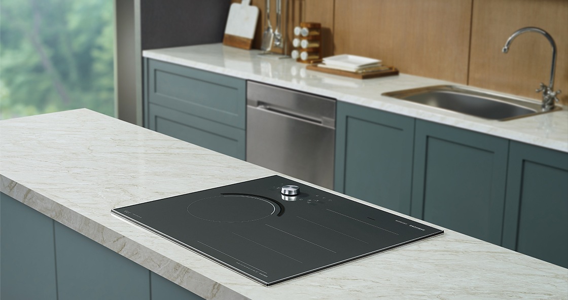 대리석으로 된 조리대 위에 전기레인지가 빌트인 방식으로 설치된 모습입니다. 뒤로 주방 용품과 싱크대가 보입니다.