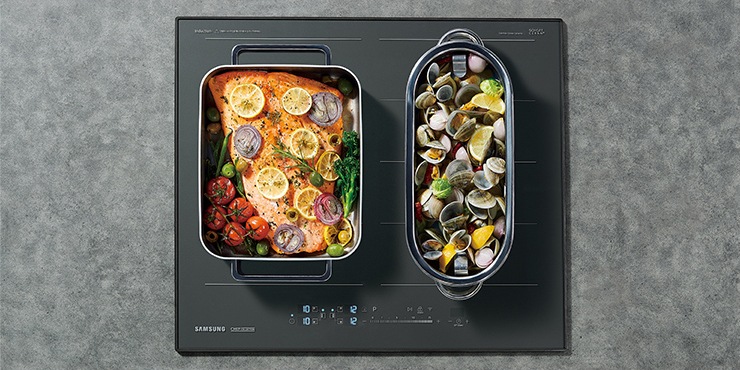 대리석으로 된 조리대 위에 전기레인지가 빌트인 방식으로 설치되어 있으며 이를 위에서 정면으로 내려다본 모습입니다. 전기레인지의 왼쪽 플렉스존에는 연어 스테이크, 오른쪽 플렉스존에는 조개찜을 조리중입니다.