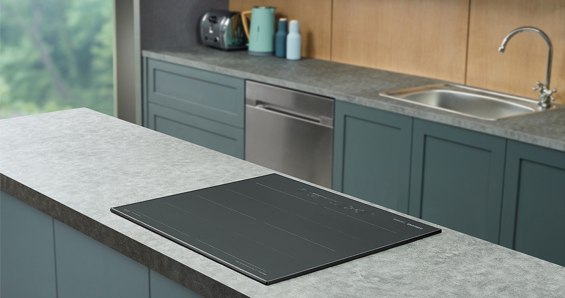 대리석으로 된 조리대 위에 전기레인지가 빌트인 방식으로 설치된 모습입니다. 뒤로 주방 용품과 싱크대가 보입니다.