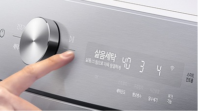 세탁기 패널 부분이 확대된 이미지입니다. 손가락으로 조작을 하고 있고 알림 창에는 삶음세탁 코스가 표시되어 있습니다.