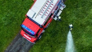 Top view of a firetruck spraying water over a field.