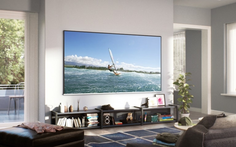 在寬敞舒適的客廳裡，有一台三星超大電視掛在牆上。螢幕上，有一名男子正在享受衝浪。