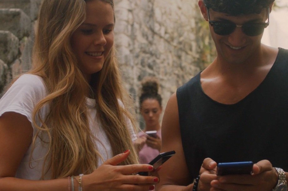 Una mujer y un hombre sonríen y miran sus teléfonos
