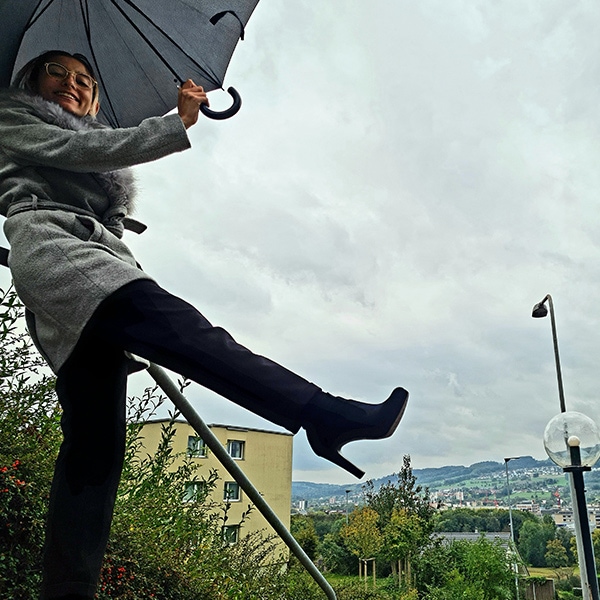 Woman kicking her legs in the air holding an umbrella
