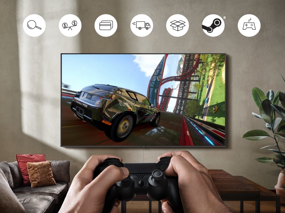 벽에 부착된 QLED TV에 레이싱 게임 화면이 보입니다. 비디오 컨트롤러로 게임을 조종하고 있는 손도 함께 보입니다. 