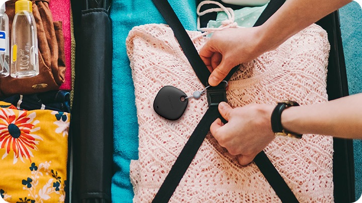 A person attaching a Galaxy SmartTag+ to the straps inside a suitcase, indicating SmartTag+ can be tied to important things.