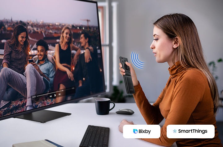 A woman speaks to the monitor. And a video is played on it. The Bixby and SmartThings icon is in the right corner.