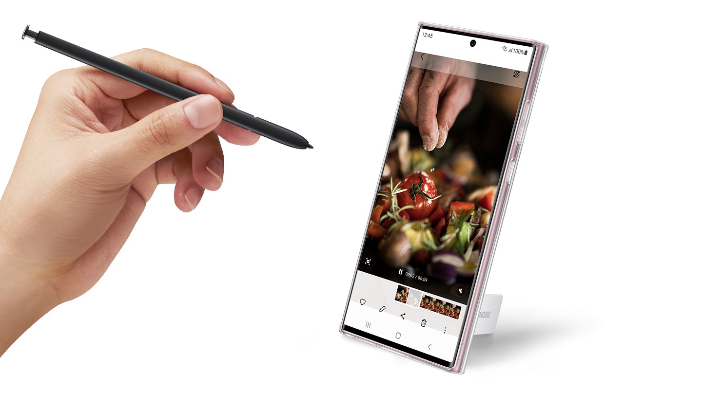 A hand holds S Pen next to Galaxy S22 Ultra, viewed from the front with a video call onscreen, and Clear Standing Cover is installed.