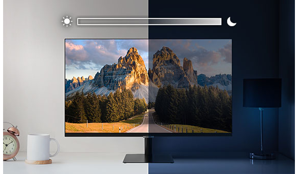 A monitor sits on top of a desk and is split into left and right sides. The left side is brightly lit while the right side is very dark. Above the screen is a slider icon with a sun on the left and a moon on the right.