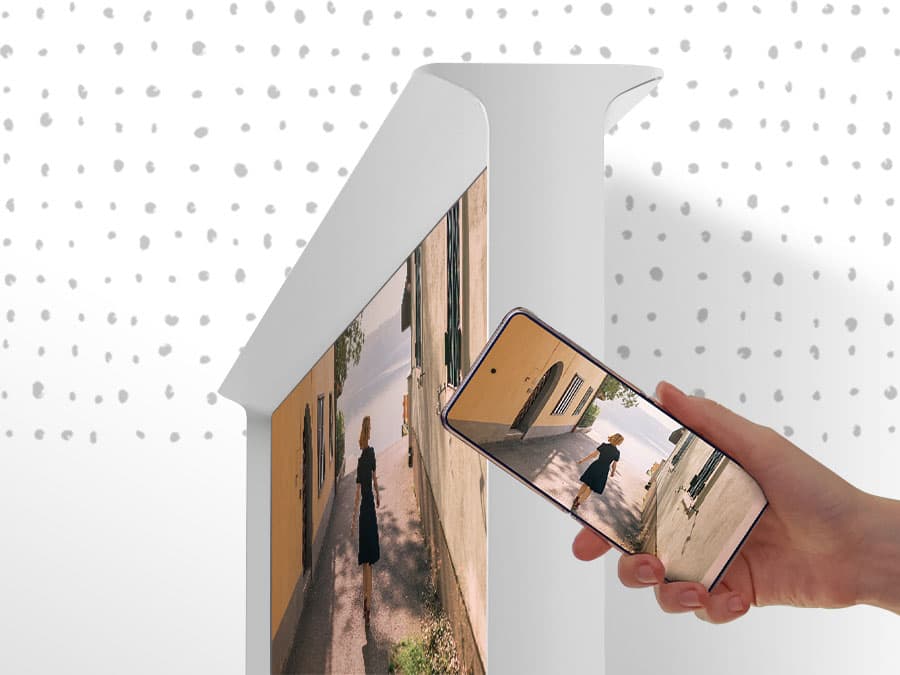 A person is tapping the side of The Serif and the content on the smartphone appears on The Serif's big screen.