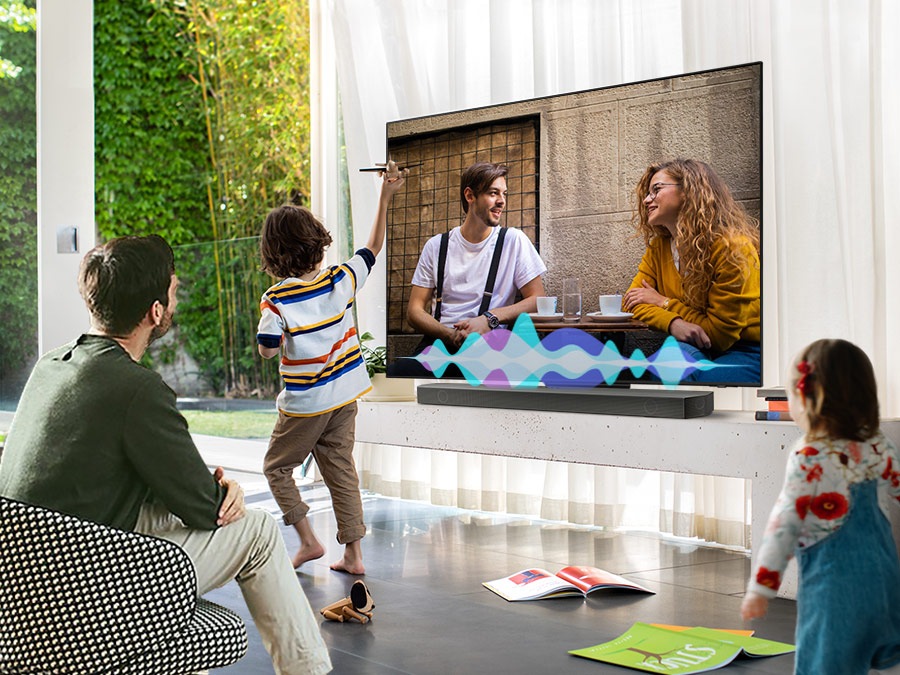 A man watches TV while his children play. Simulated sound wave graphics show Active Voice Amplifier technology optimizing dialogue so it can be heard more clearly in noisy environments.