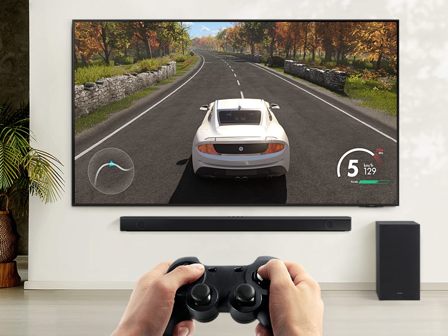 A user is enjoying soundbar’s Game Mode while playing a racing game on their TV connected to soundbar and subwoofer.