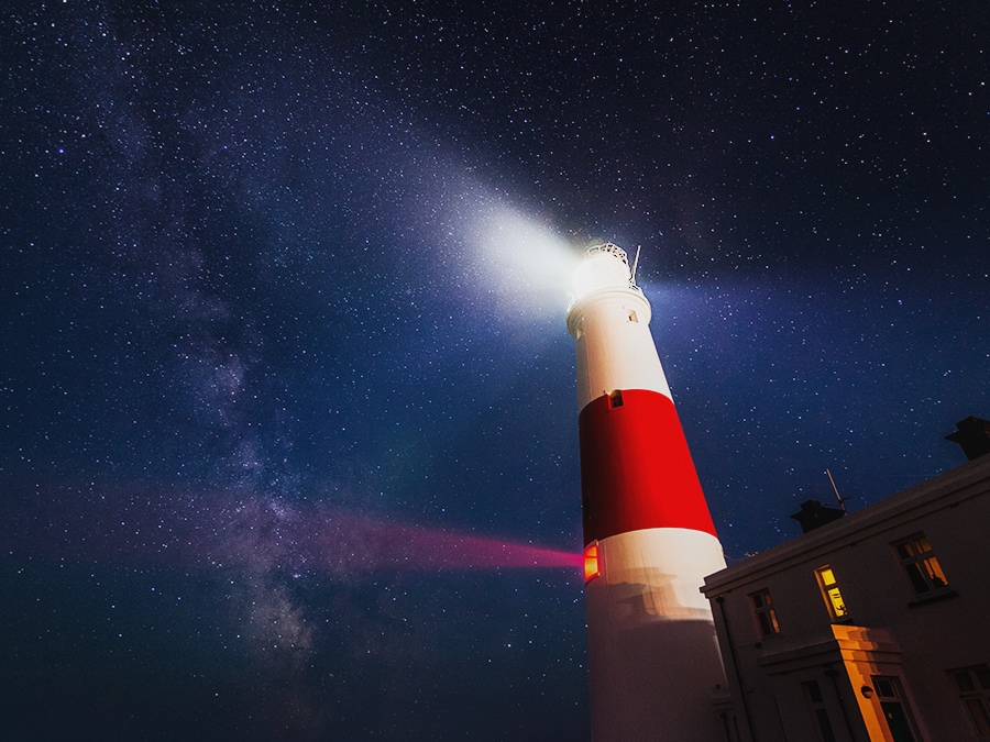 A lighthouse is shining light from its beacon. The stars look less vivid and clear without Fine HDR Pro technology.