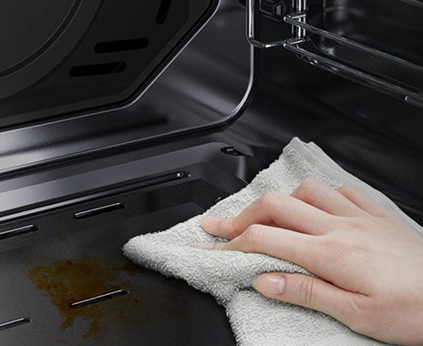 A person is wiping down the oven’s Easy Clean surface using just a cloth.