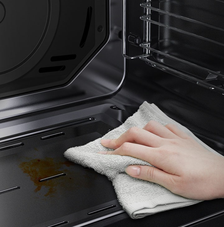 A person is wiping down the oven’s Easy Clean surface using just a cloth.